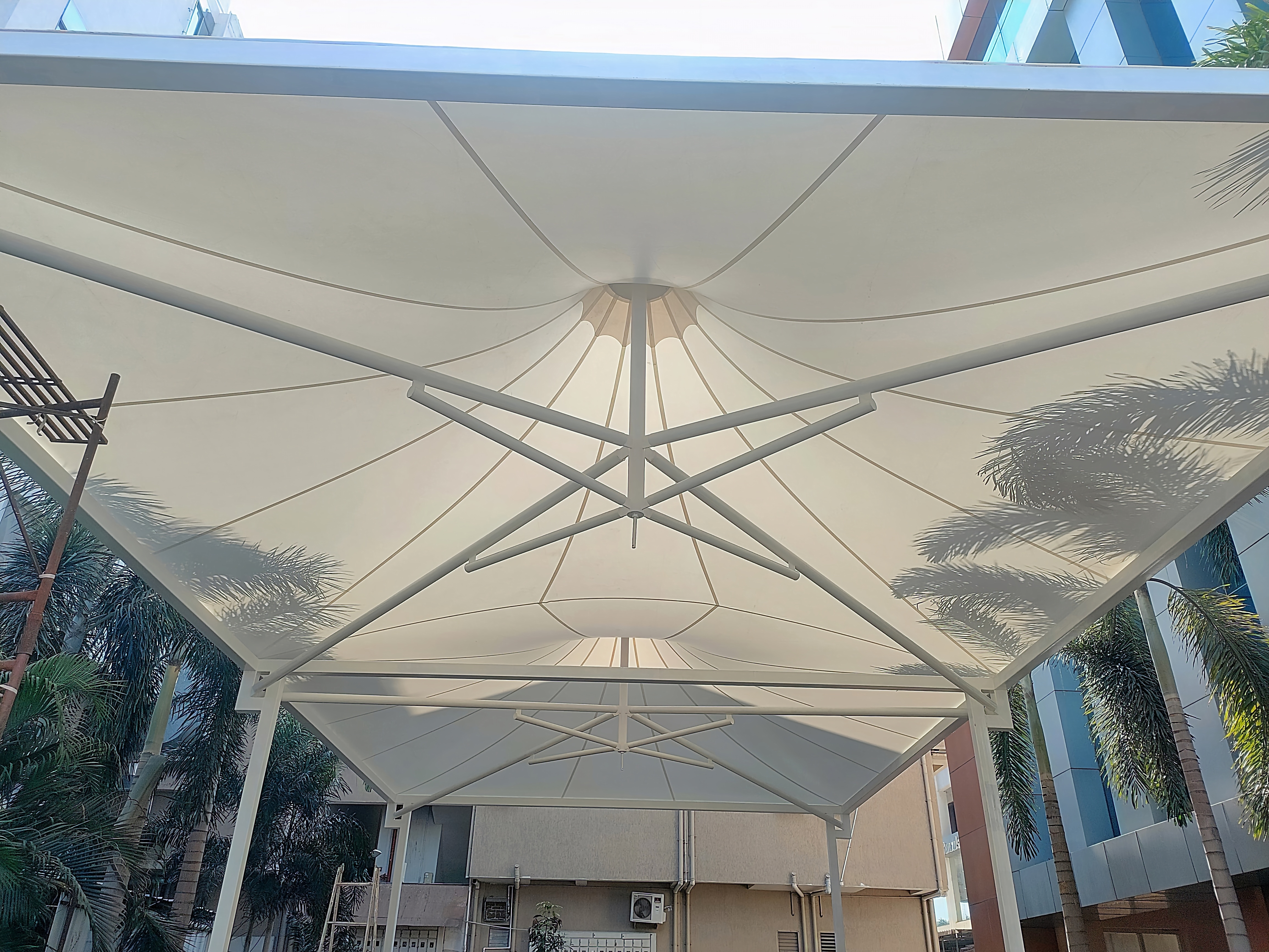 Layered conical tensile canopy over an entrance breezeway