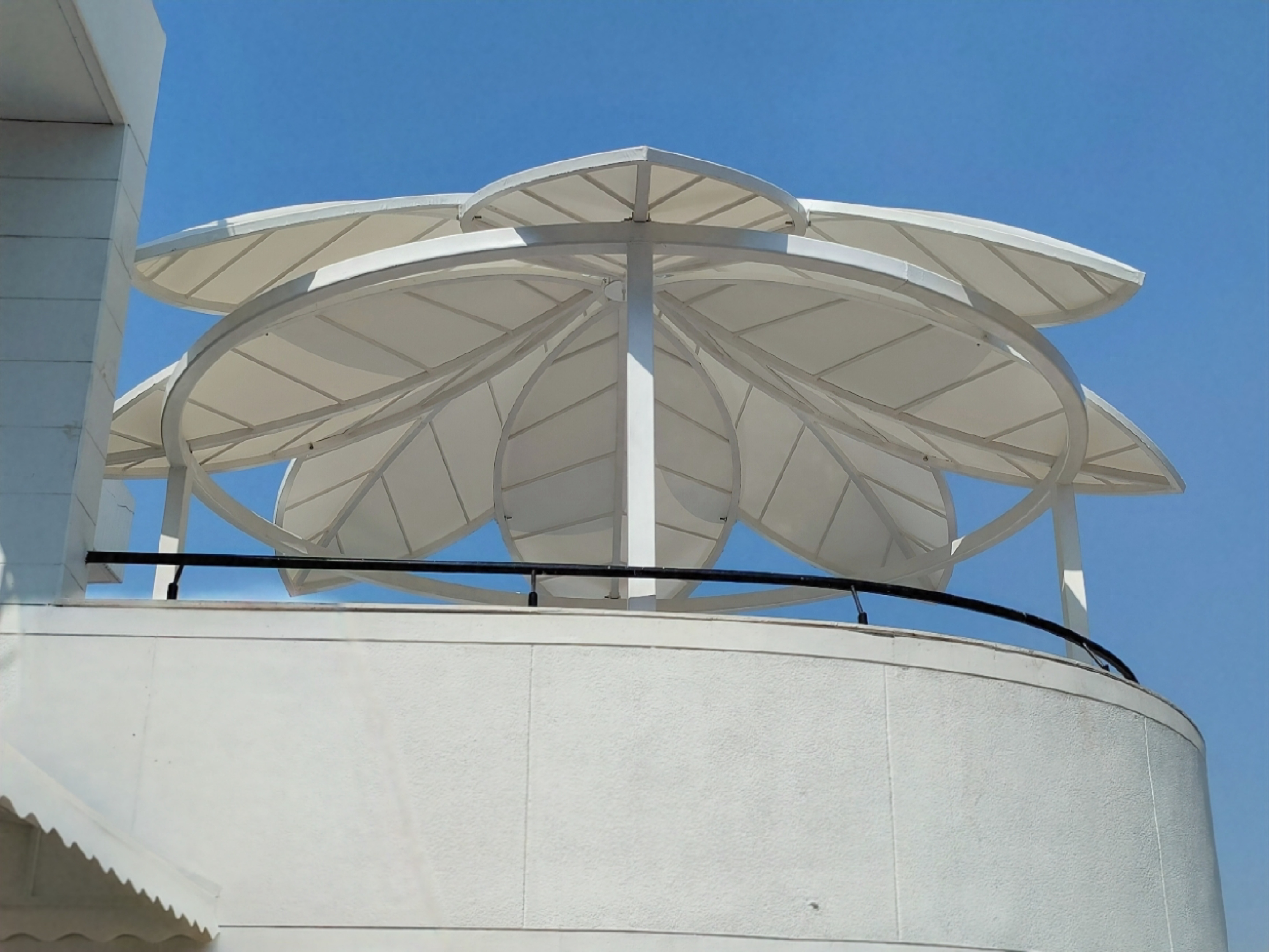 Multi-petal flower-shaped tensile canopy on a rooftop terrace
