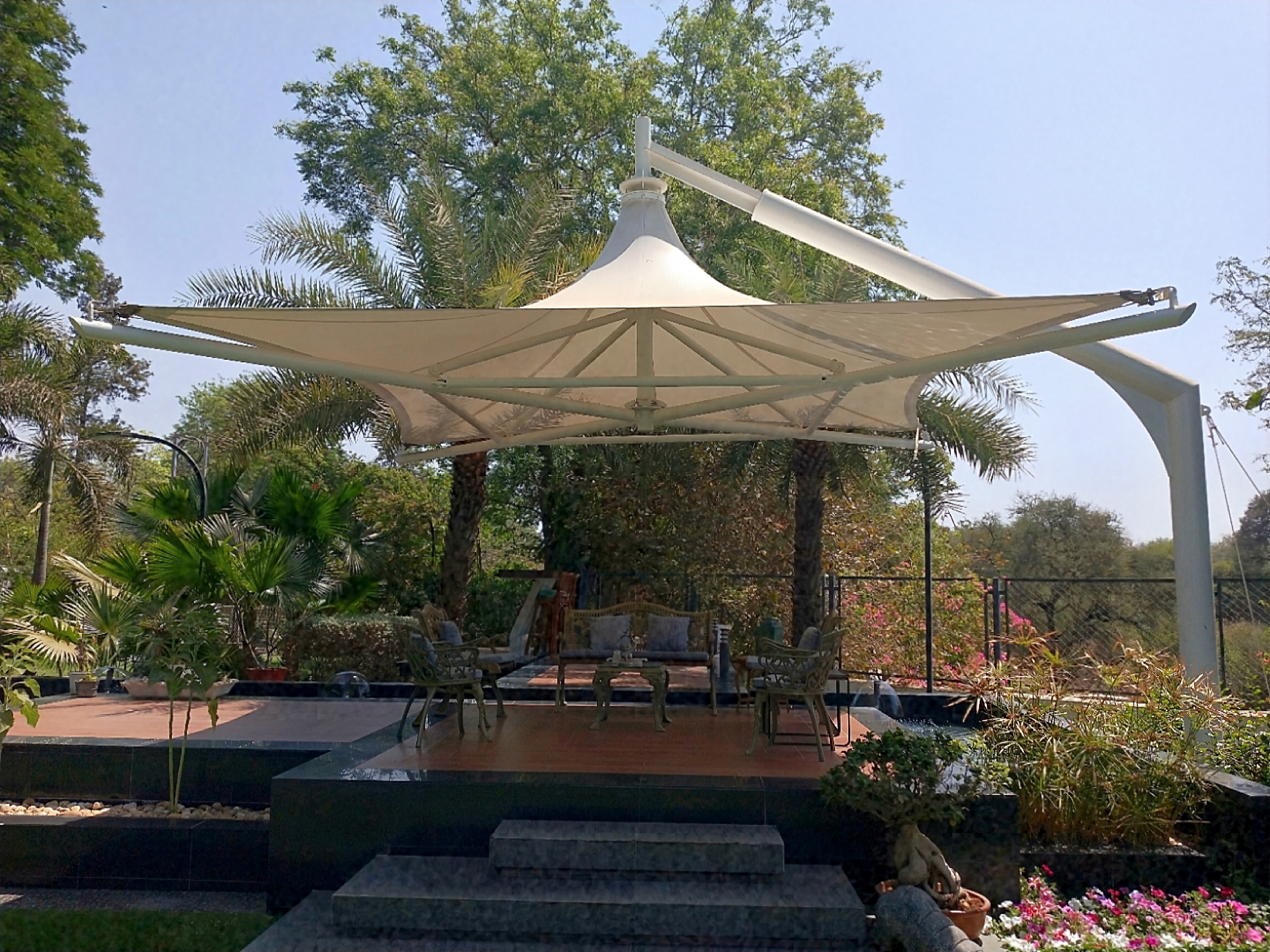 Single-mast tensile umbrella canopy over a garden patio